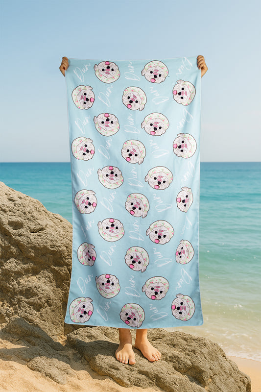 Towel with donut pattern held by a person on a beach