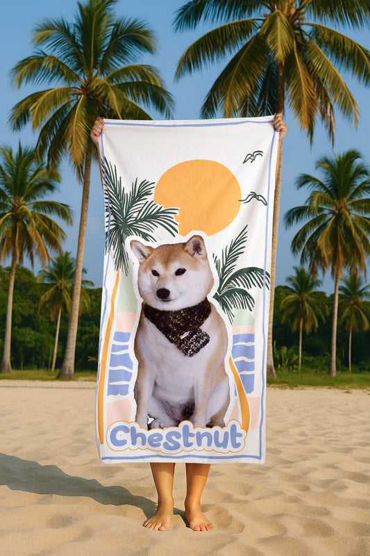 Person holding a beach towel with a dog illustration and 'Chestnut' text on a beach with palm trees in the background.