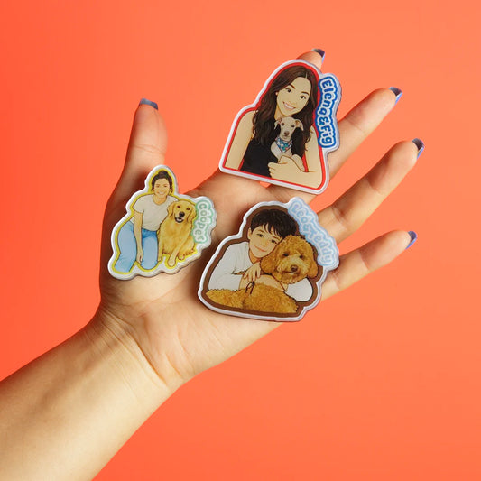 Hand holding three stickers with images of people and dogs on an orange background