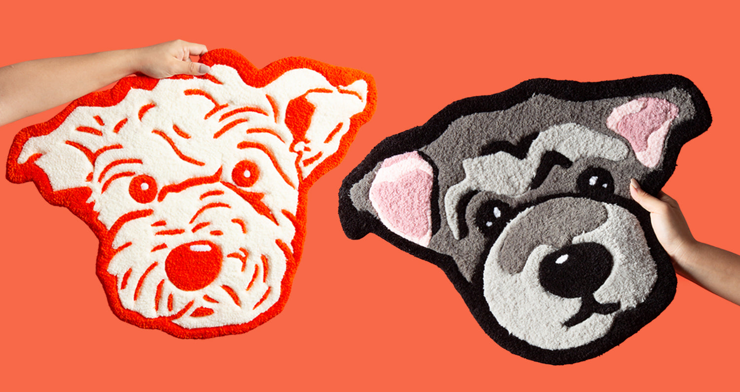 Two dog-shaped rugs, one red and white, the other gray and black, held by hands against an orange background.