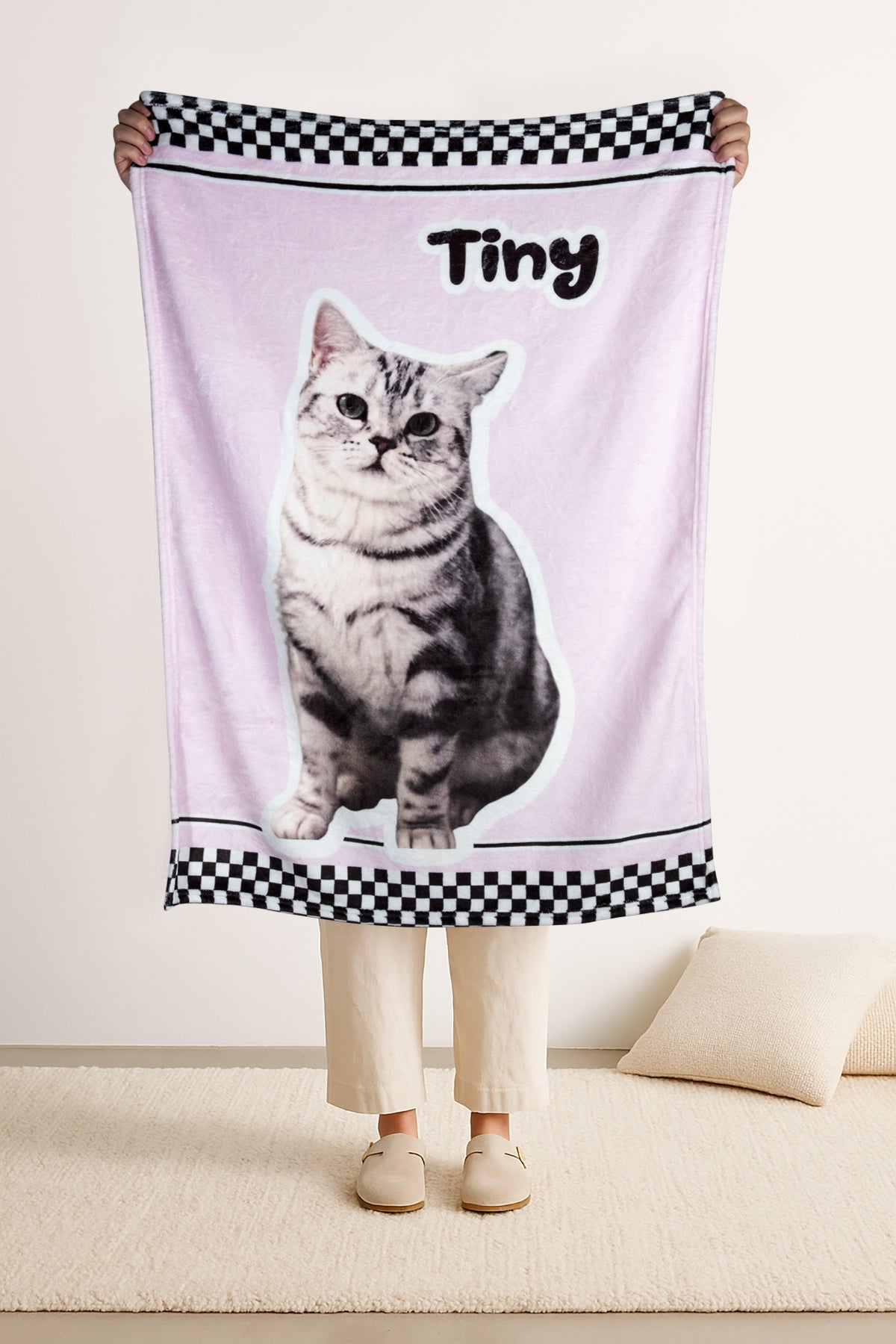 Person holding a towel with a cat design and 'Tiny' text on a light background