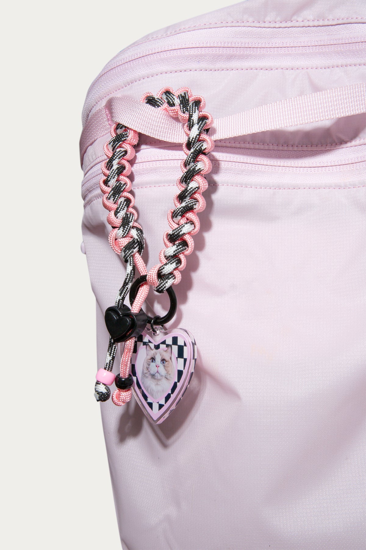 Pink braided strap with heart-shaped charms on a white background