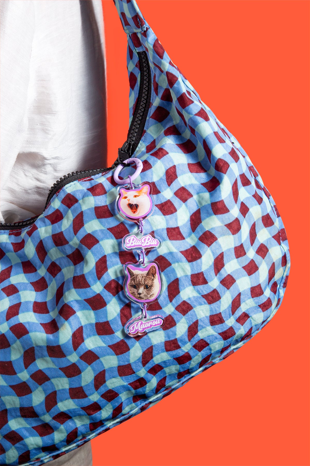 Patterned bag with cat-themed keychains on an orange background