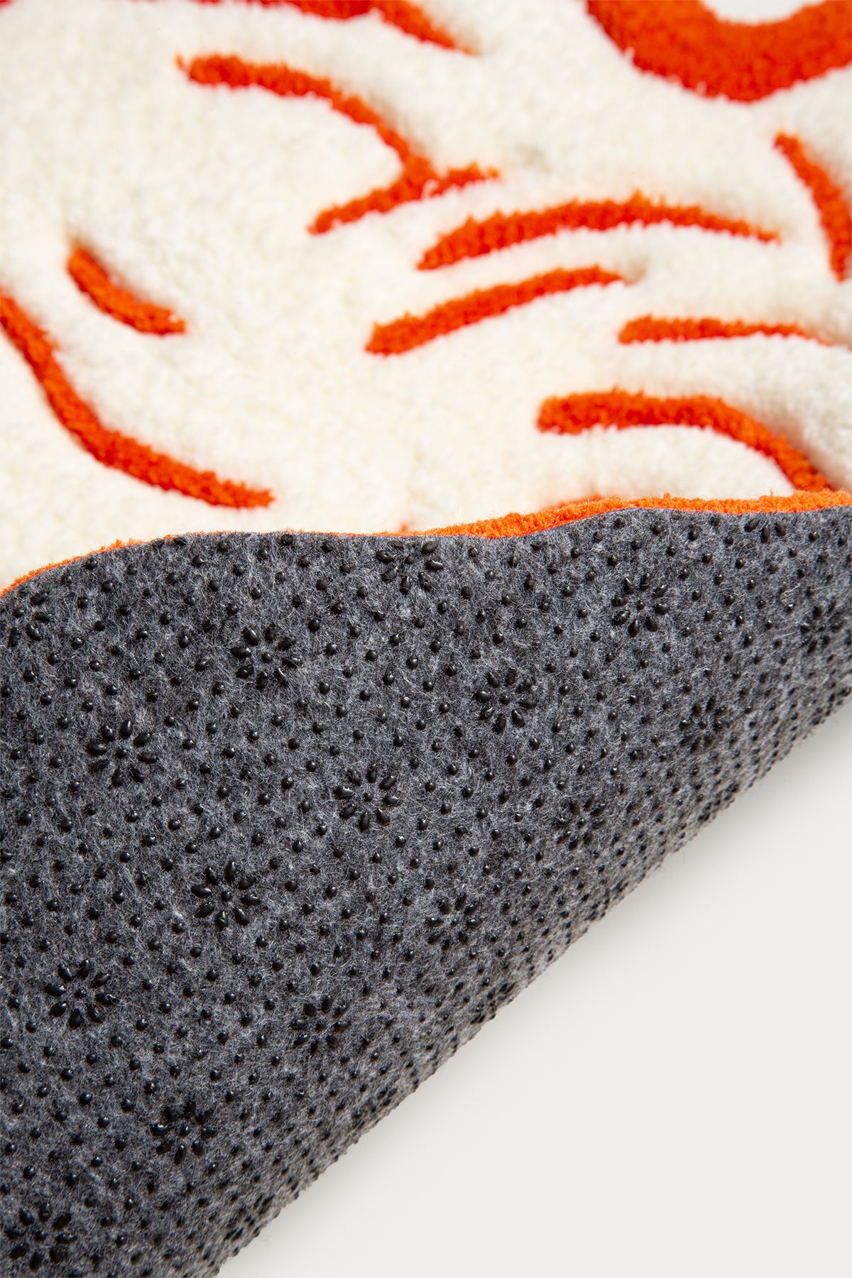 Close-up of a textured surface with orange and white pattern on top and gray material underneath.