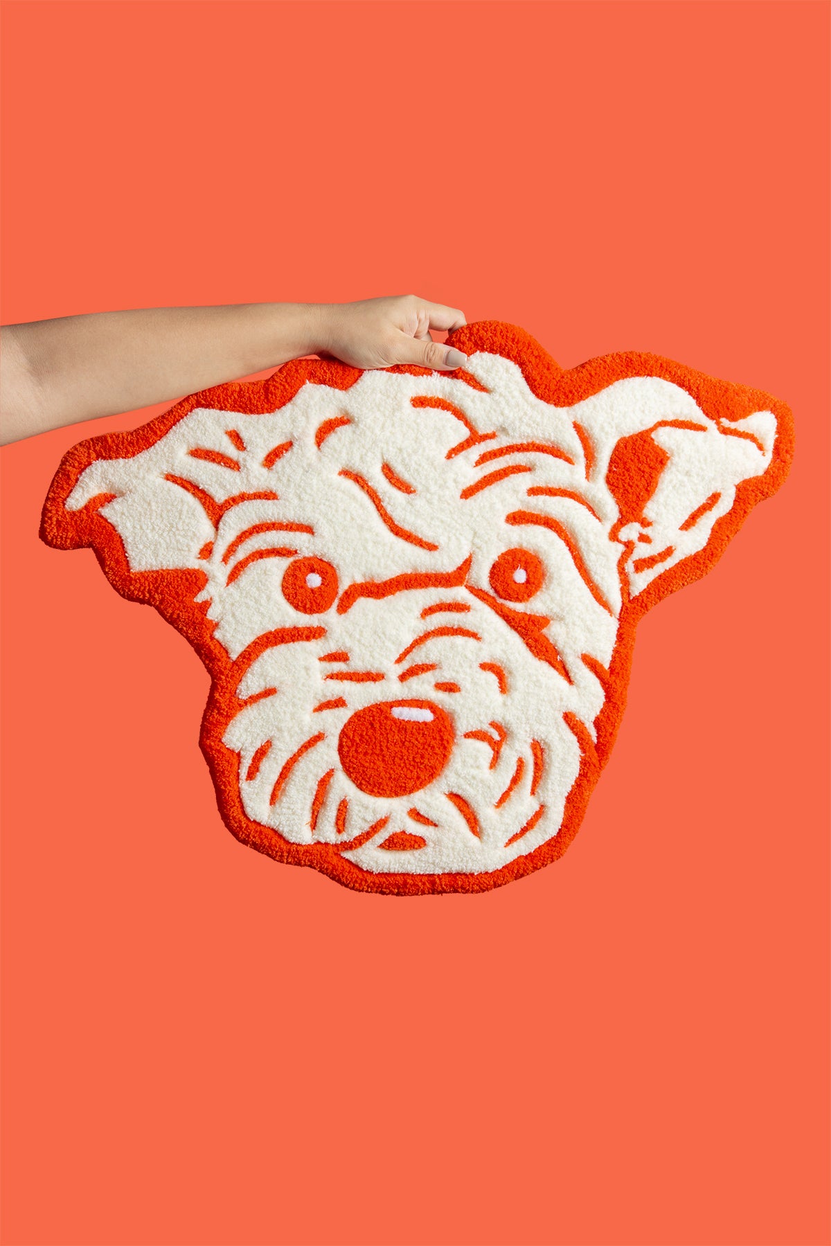 Tiger-shaped rug with a person holding it against an orange background